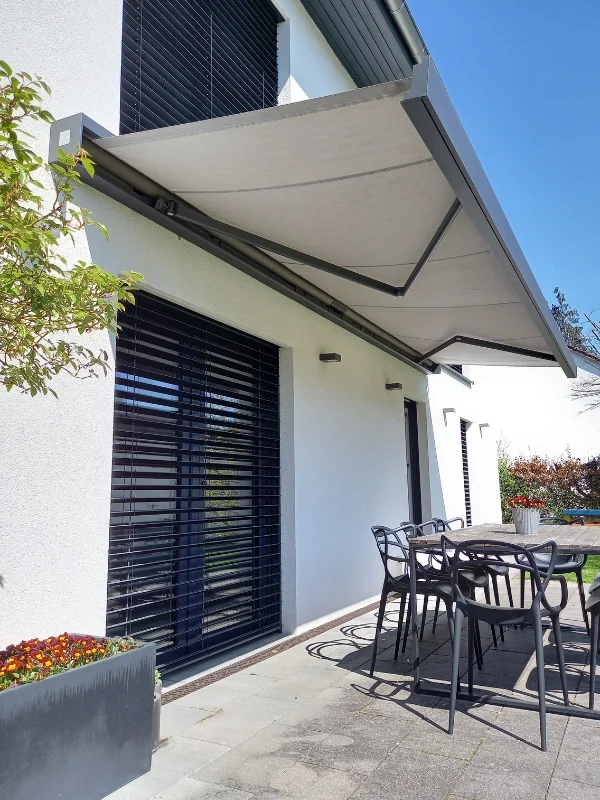 Große Gelenkarmmarkise schützt die Terrasse in Barsinghausen und schafft Schatten über Sitzgruppe und Glasfront zuverlässig.
